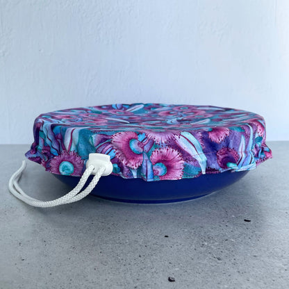 Produce Pod reusable bowl cover in a Gum blossom print fitted snugly over a  serving dish on kitchen countertop.