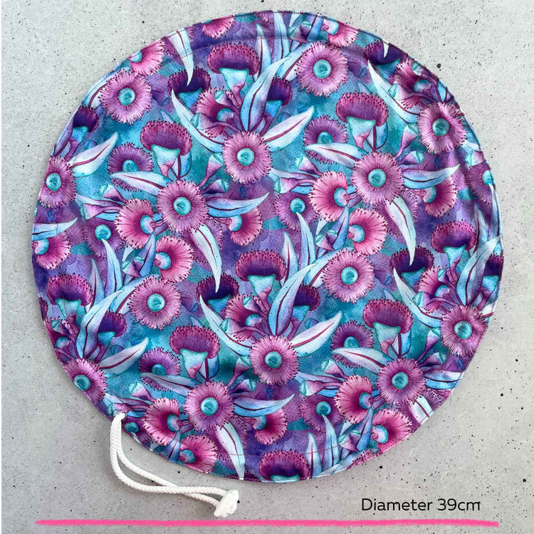 An extra large thirty nine centimeter Produce Pod reusable bowl cover in a Gum blossom print laid out on a surface top view.
