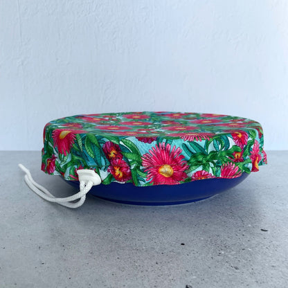 Produce Pod reusable bowl cover in a Sea fig print fitted snugly over a blue serving dish on a stone countertop.