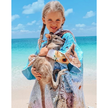 Young girl on a sandy beach wearing the Kalbarri print quick dry kids hooded towel.