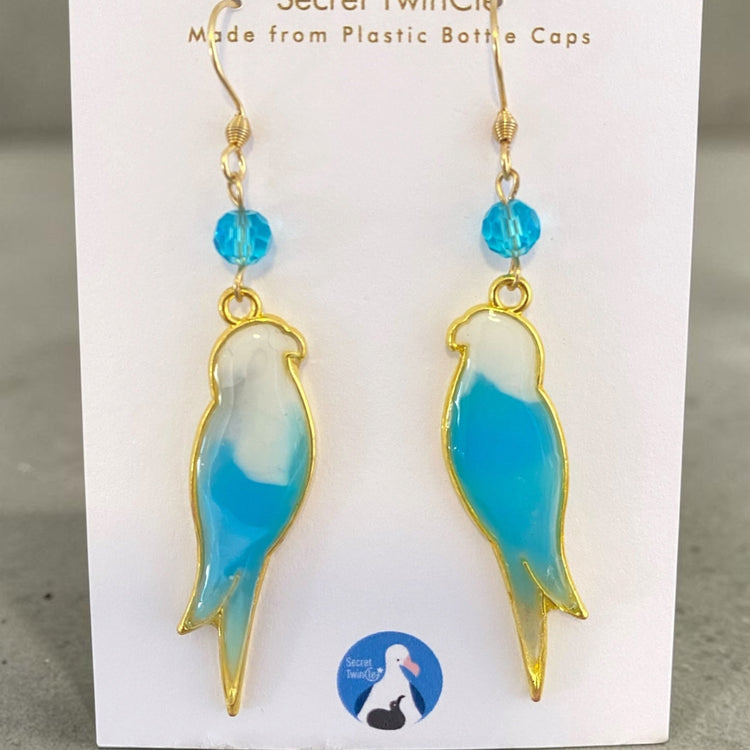 A pair of handmade upcycled plastic bird dangle statement earrings featuring artisan color marbling, made in Australia. Light blue and white variant.