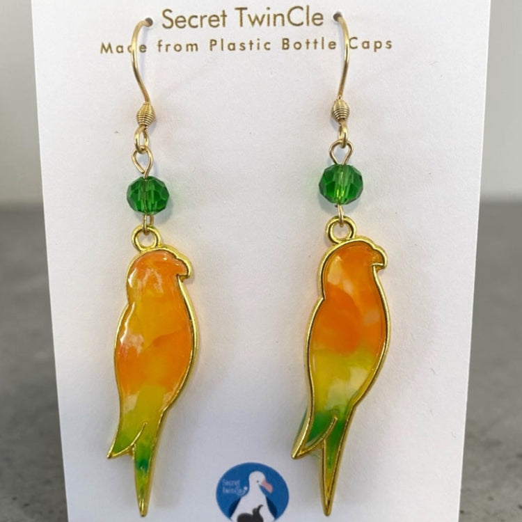 A pair of handmade upcycled plastic bird dangle statement earrings featuring artisan color marbling, made in Australia. Orange and light green variant.