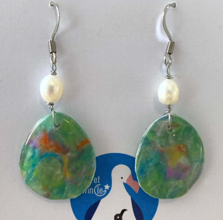 A pair of handmade recycled plastic drop dangle statement earrings in a marbled green nebula pattern, adorned with freshwater pearls.