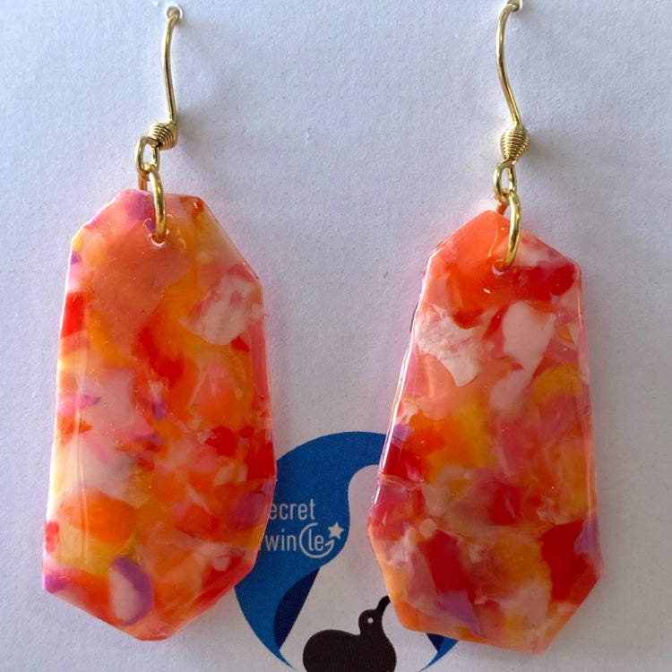 A pair of handmade upcycled plastic Full Bloom dangle earrings in a vibrant orange red marbled floral design, made in Australia.