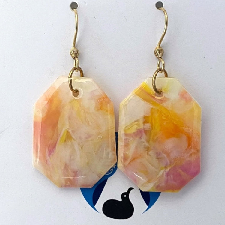 A matching pair of handmade recycled plastic statement earrings in a geometric octagon dangle design with marbled pastel pink and white tones.