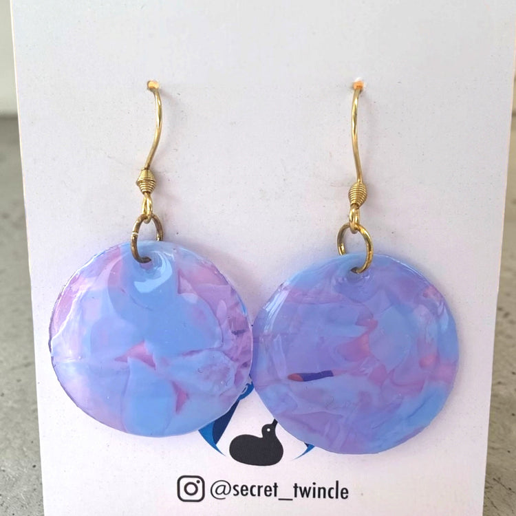 A pair of handmade upcycled plastic statement earrings featuring a geometric round circle dangle design in translucent clear purple, made in Australia.