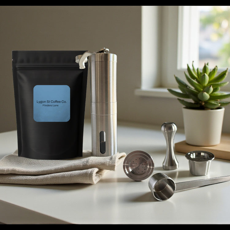 Pod Star barista pack for Espressotoria coffee machines featuring two stainless steel reusable pods, a manual coffee grinder, an espresso tamper, a scoop, and premium coffee beans on a kitchen banchtop.