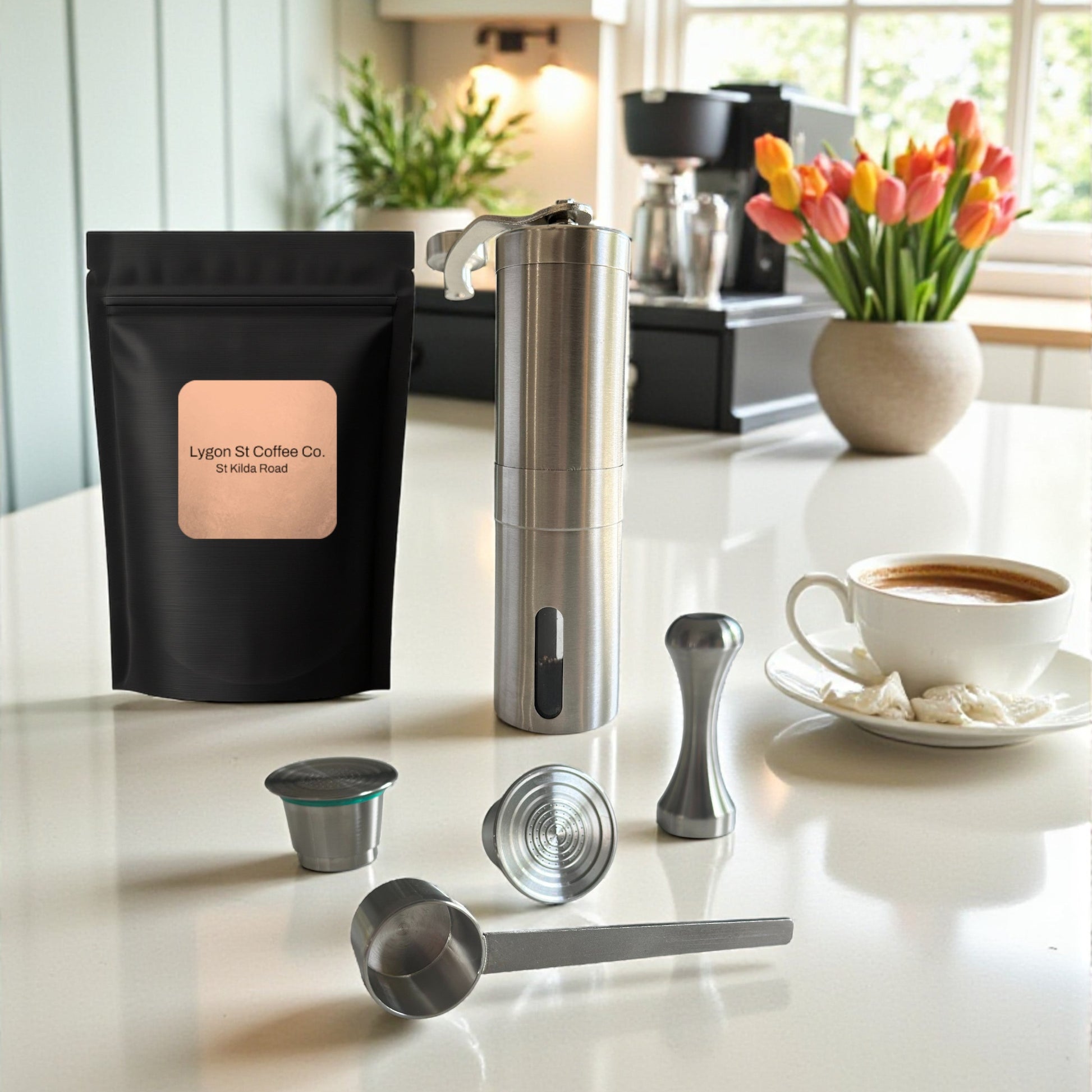 Pod Star barista pack for Nespresso Original line coffee machines featuring two stainless steel reusable pods, a manual coffee grinder, an espresso tamper, a scoop, and premium coffee beans on a kitchen countertop with a cup of coffee.
