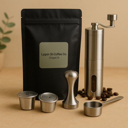 Pod Star barista pack for Nespresso Original line coffee machines featuring two stainless steel reusable pods, a manual coffee grinder, an espresso tamper, a scoop, and premium coffee beans on a beige background with coffee beans.