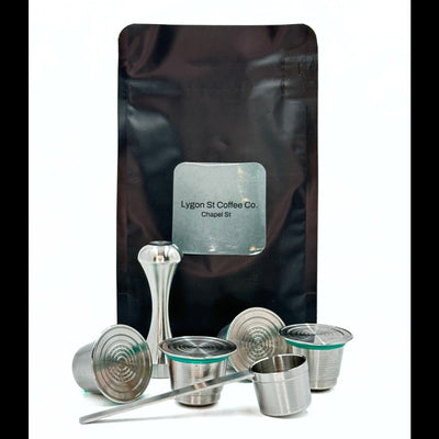 Pod Star family pack for Nespresso Original line coffee machines featuring four stainless steel reusable capsules, an espresso tamper, and a coffee measuring scoop on a white background.