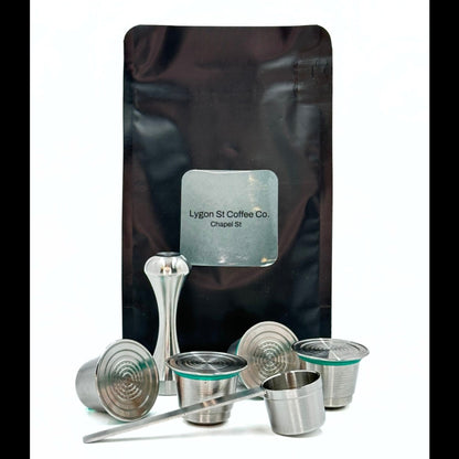 Pod Star family pack for Nespresso Original line coffee machines featuring four stainless steel reusable capsules, an espresso tamper, and a coffee measuring scoop on a white background.