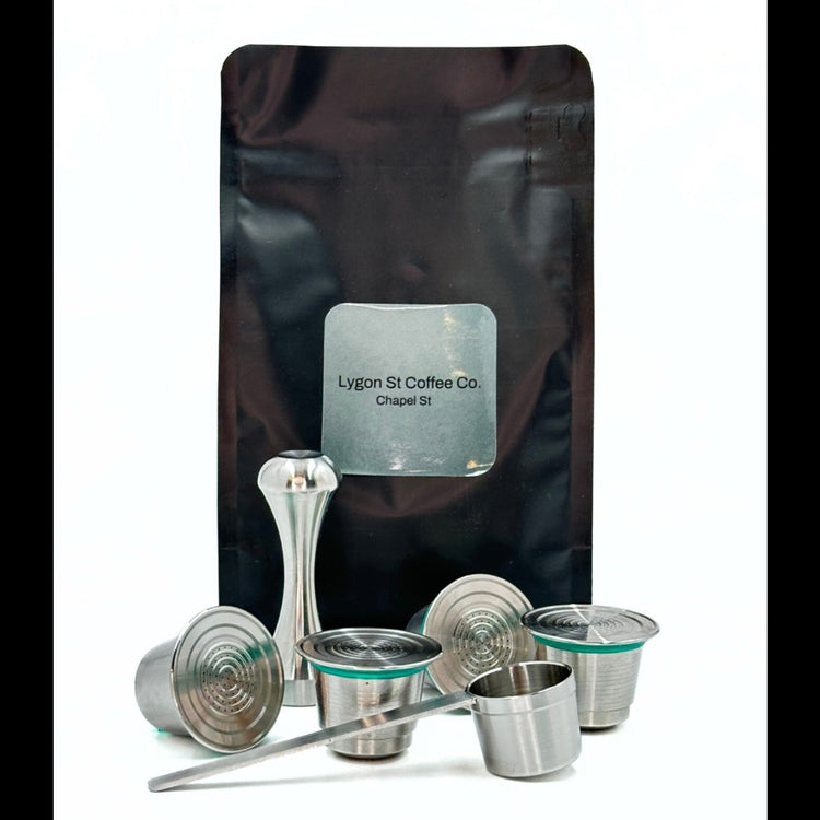 Pod Star family pack for Nespresso Original line coffee machines featuring four stainless steel reusable capsules, an espresso tamper, and a coffee measuring scoop on a white background.