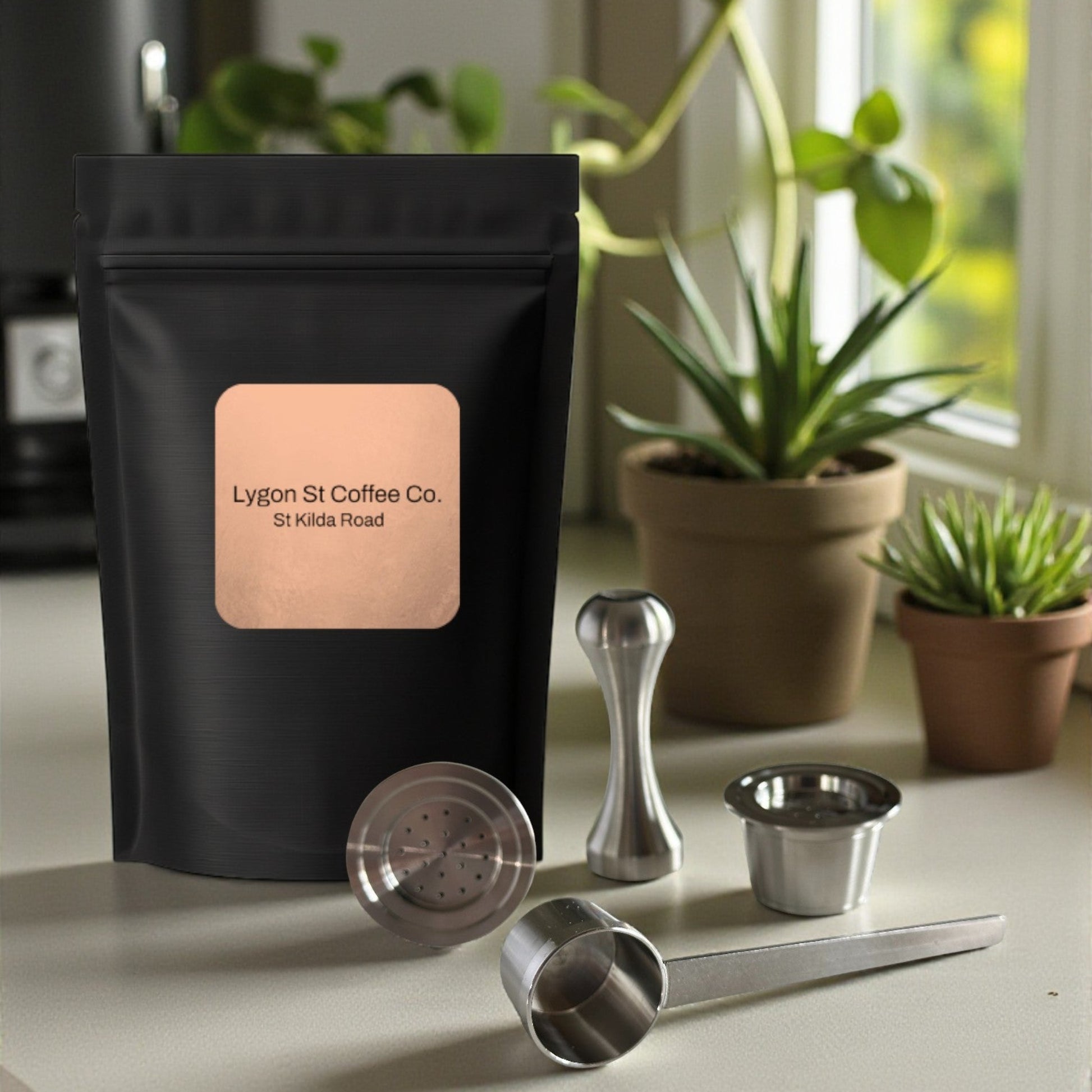 Pod Star starter pack for Espressotoria coffee machines featuring two refillable stainless steel capsules, an espresso tamper, a measuring scoop, and fresh coffee grounds on a kitchen countertop.