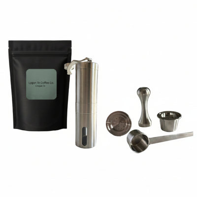 Pod Star ultimate pack for Espressotoria coffee machines featuring four stainless steel reusable capsules, a manual burr grinder, an espresso tamper, a scoop, and coffee beans on a white background.