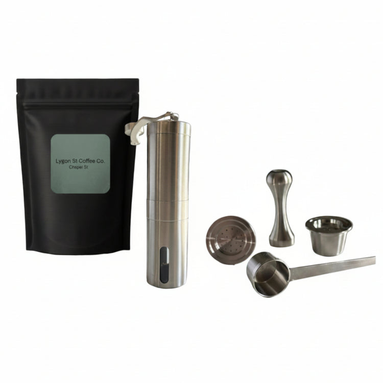 Pod Star ultimate pack for Espressotoria coffee machines featuring four stainless steel reusable capsules, a manual burr grinder, an espresso tamper, a scoop, and coffee beans on a white background.