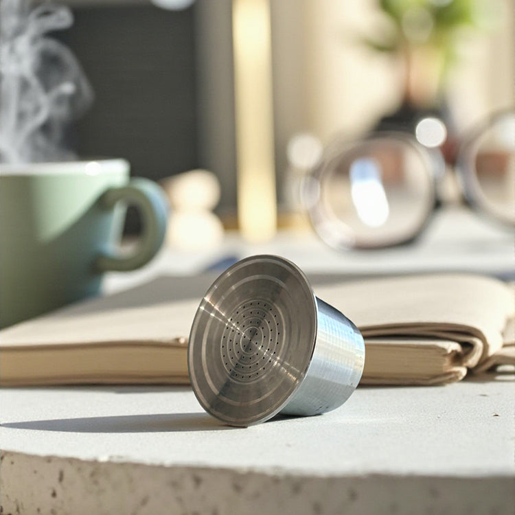 Pod Star marine-grade 316L stainless steel reusable coffee capsule shown side on on a kitchen countertop, designed for Nespresso Original line machines.