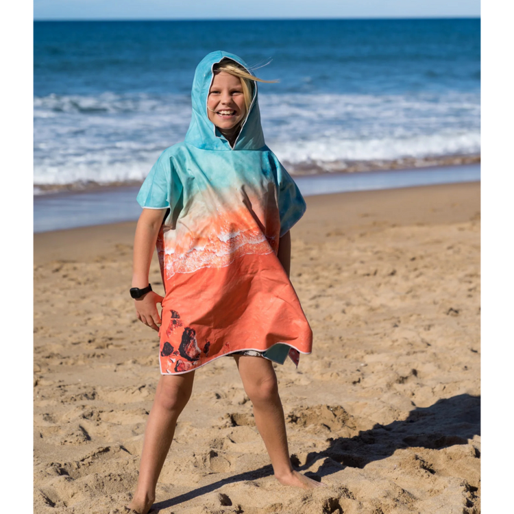 Child walking near the ocean wearing a sand free kids beach poncho towel in the Kimberley print.