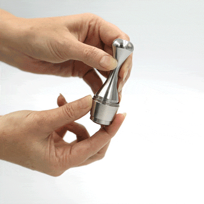 Solid stainless steel coffee pod tamper tool designed for packing reusable capsules, shown being used to tamp a reusable coffee pod.