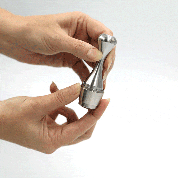 Solid stainless steel coffee pod tamper tool designed for packing reusable capsules, shown being used to tamp a reusable coffee pod.