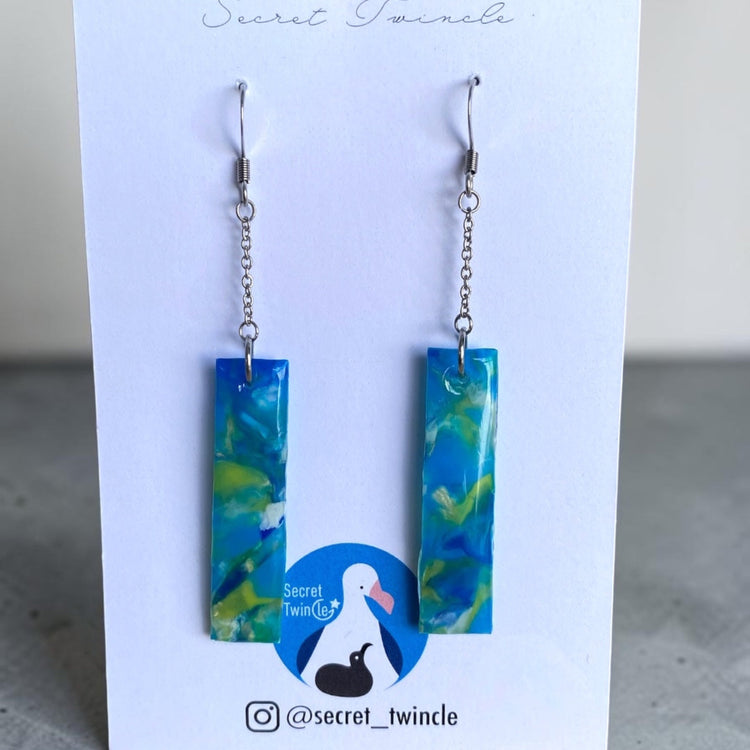 Flat lay studio presentation of the blue and green geometric rectangular chain dangles, offering an ideal sustainable jewelry gift option.