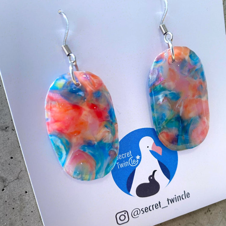 Flat lay studio shot of the blue and orange oval-shaped upcycled dangles, showing an eco-friendly gift choice for sustainable fashion collections.