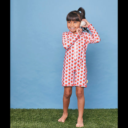 Child wearing the long sleeve strawberry swim sunsuit in a studio setting.