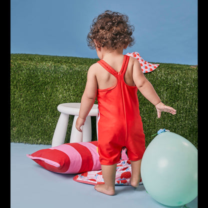 Young girl wearing a Tyoub strawberry sundae print zootie swimsuit showing back view with a blue balloon.