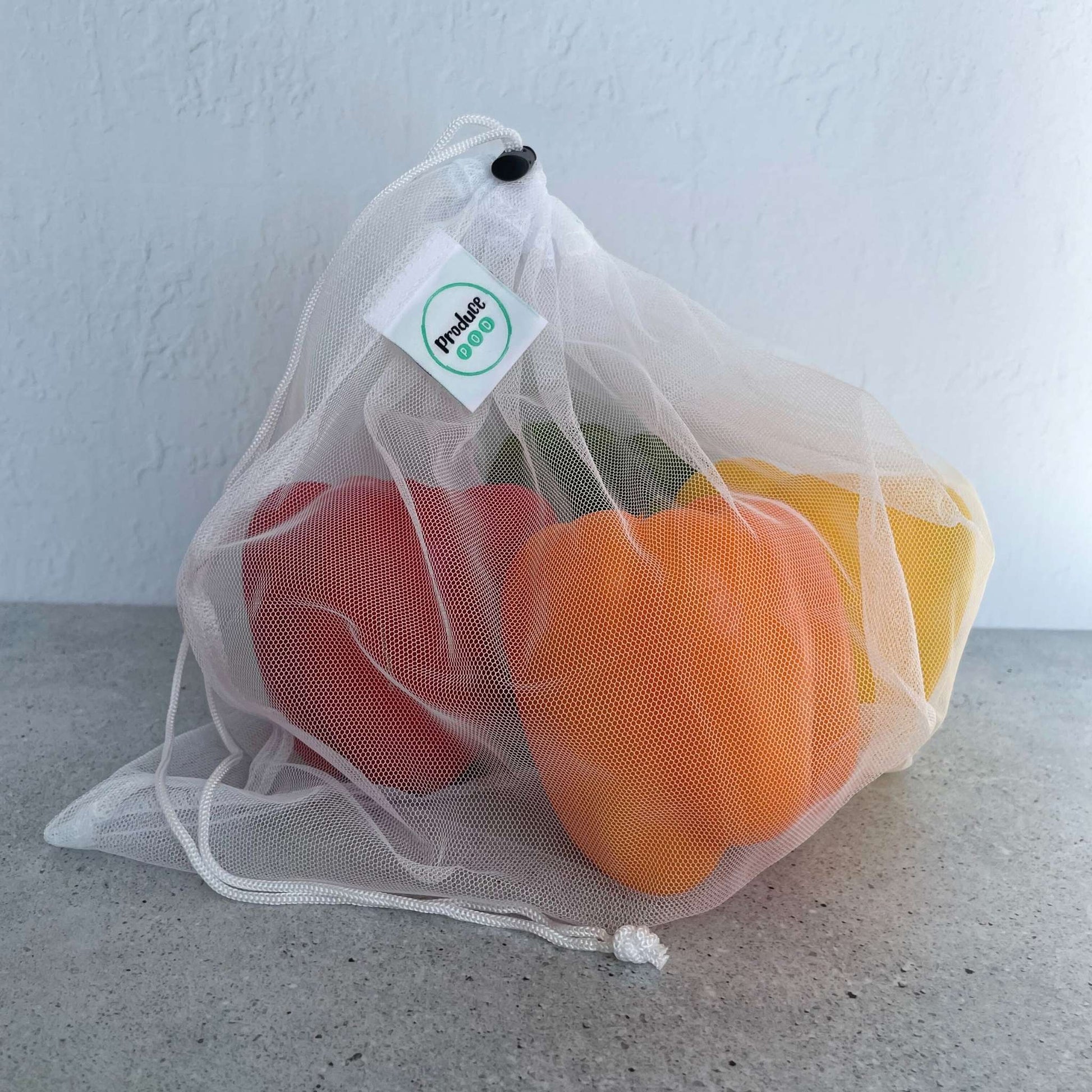 See through recycled mesh grocery bag holding capsicum for quick scanning at the supermarket checkout.