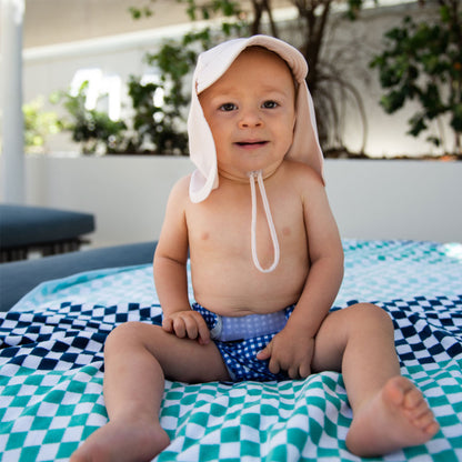 Baby wearing a cream Tyoub legionnaires sun hat for Sun Smart UV coverage outdoors in Australia.