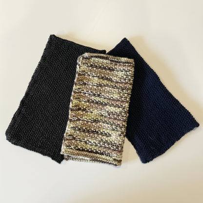 A selection of hand-knitted upcycled acrylic scrubbing cloths stacked neatly together, rescued from industrial textile mill ends, on a white background.
