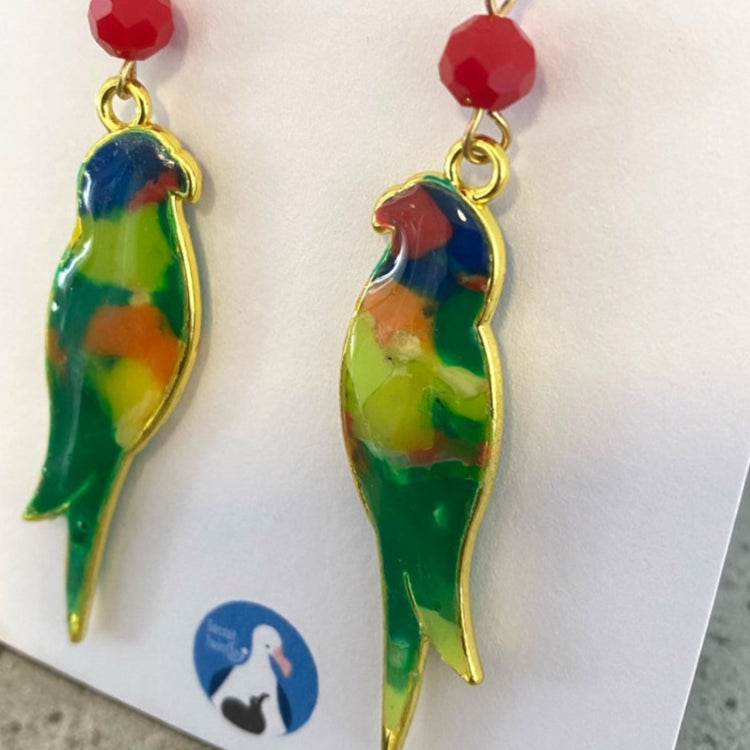 Detailed macro view highlighting the unique color pattern and smooth edge finish of the recycled bottle cap bird earrings.