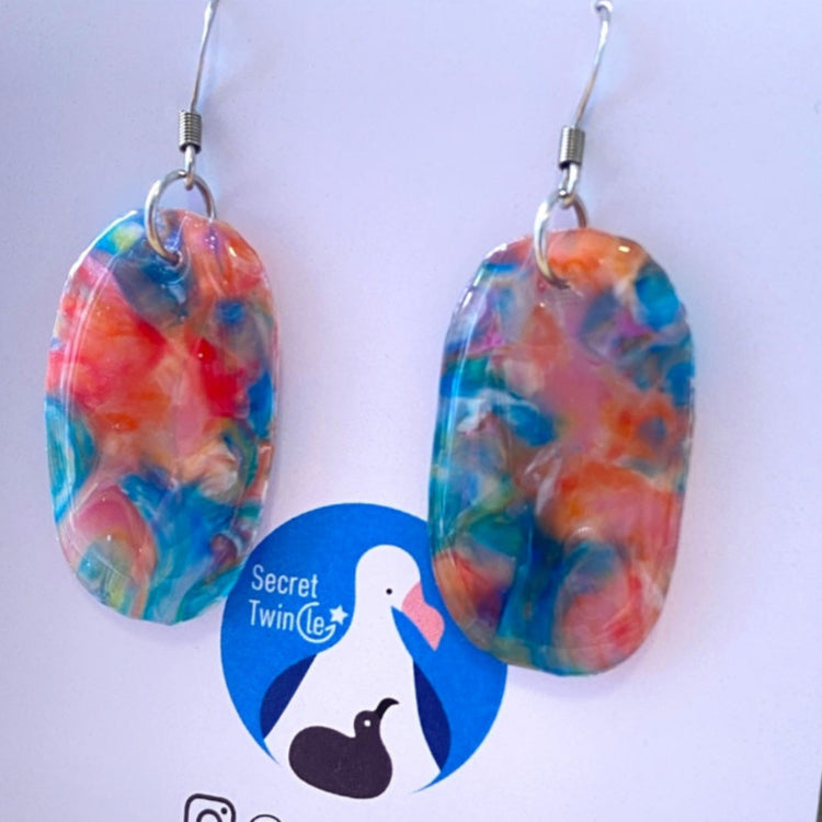 Detailed close-up highlighting the unique marbled surface texture and artisan blue and orange color mix of the recycled plastic earrings.