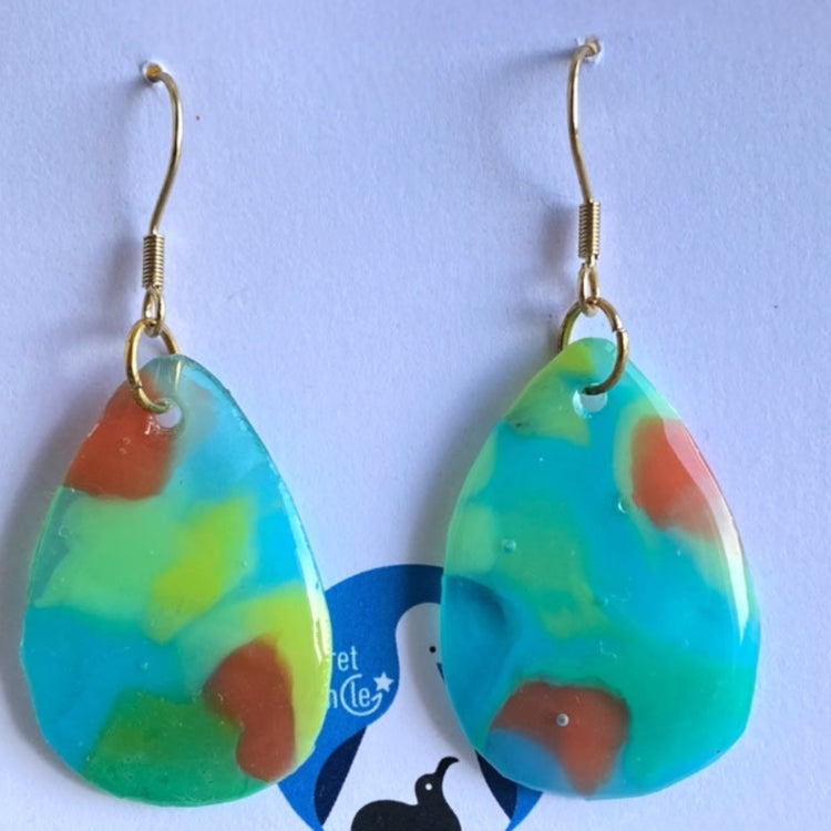 Close-up view of the unique marbling pattern and texture of the clear blue upcycled plastic dangle earrings.