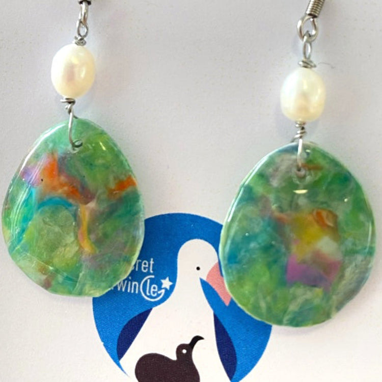 Close-up detail of the artisan green nebula swirls on eco-friendly plastic drop dangle earrings finished with delicate pearls.