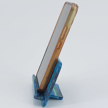 Side profile of the upcycled plastic mobile phone cradle, showing the ergonomic viewing angle and space for charging cords when a phone is upright.