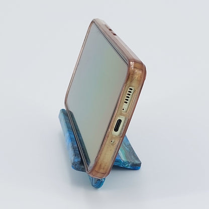 Side profile of the upcycled plastic mobile phone cradle, showing the ergonomic viewing angle and space for charging cords.
