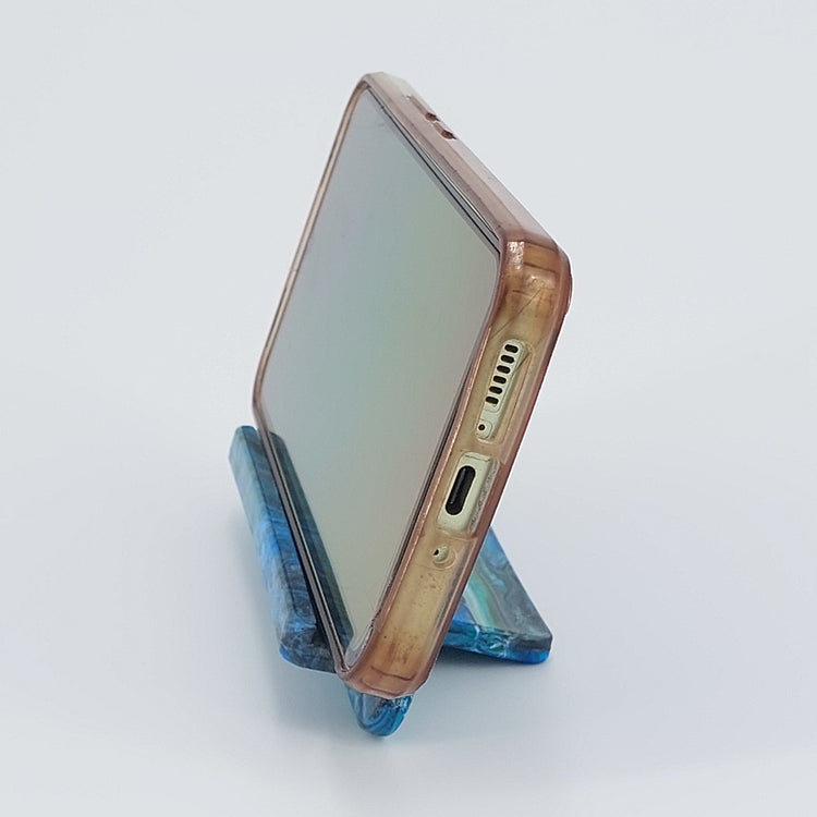 Side profile of the upcycled plastic mobile phone cradle, showing the ergonomic viewing angle and space for charging cords.