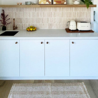 Franklin long natural woven washable kitchen runner mat placed in front of white modern cabinetry.