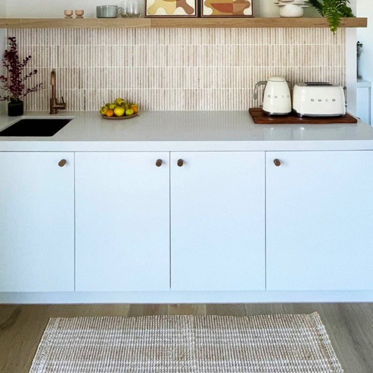 Franklin long natural woven washable kitchen runner mat placed in front of white modern cabinetry.