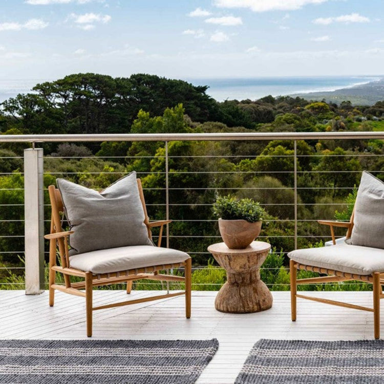 Cornell Lite grey striped washable outdoor mats placed between patio chairs on a balcony deck.