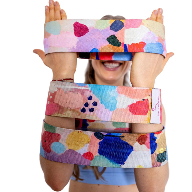 Wild Mingo set of 3 fabric resistance bands featuring Joy printed artwork. Complete light medium heavy loop pack in Australia. Held by model.