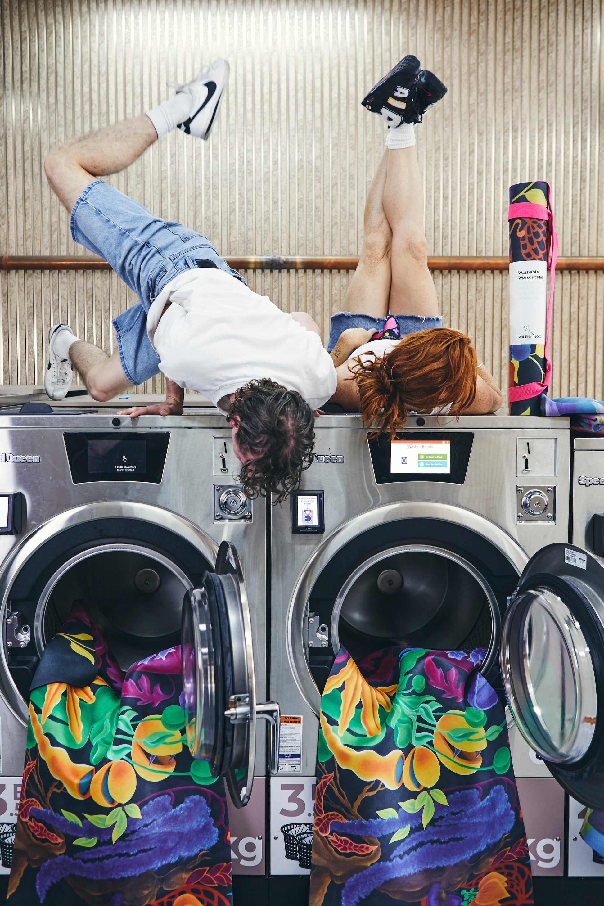 Two people on top of commercial washing machines washing Wild Mingo Pink Lady Yoga Mats