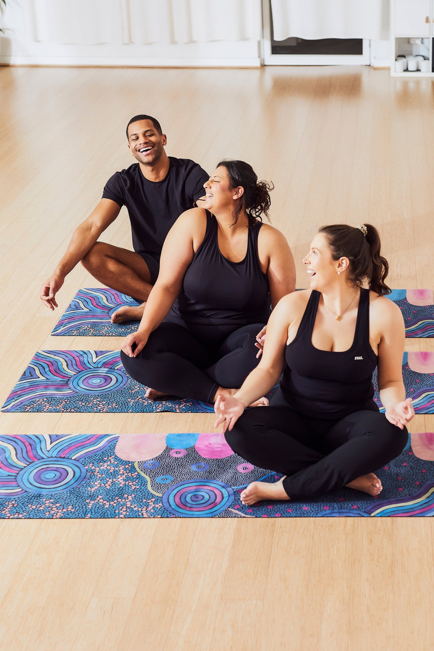 Yoga Mat | Wild Mingo | Oorunye Recycled Rubber & Microsuede Non-Slip three unrolled on a studio floor with three people