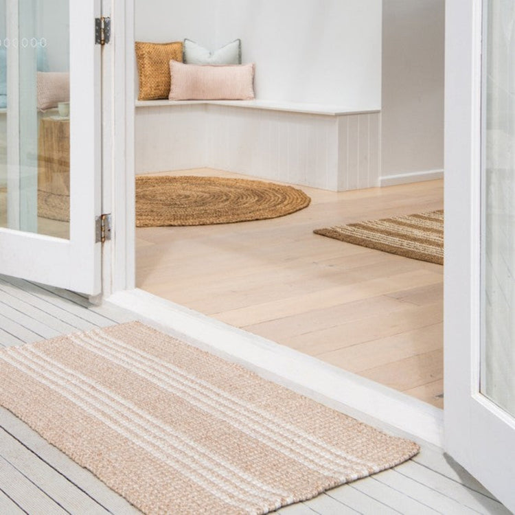 Zebra Home Franklin natural and white stripe outdoor doormat and matching area rug styled at a balcony doorway.