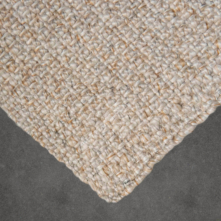 Close-up texture and finished corner detail of the Lodge Lite natural beige woven recycled plastic indoor outdoor mat by Zebra Home.
